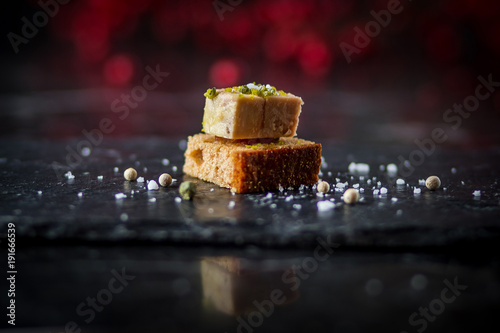 isolated foie gras toast on black plate with sea salt sprinkles