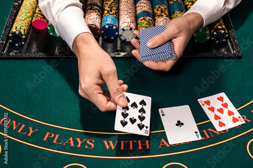 Close up of holdem dealer with playing cards and chips on green table