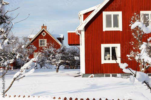 Röda bostadshus av trä omgivna av snö