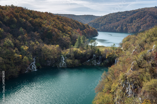 Two lakes showing the different levels and heights of Plitvice Lakes National Park. This was taken in the fall in Croatia. There are two waterfalls rushing water from the higher elevation to the lower