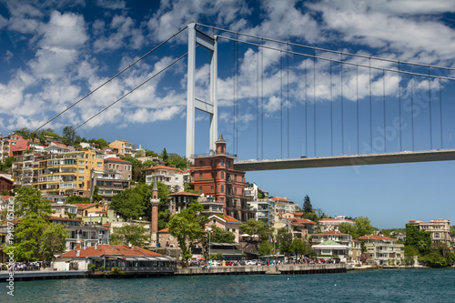 View of Fatih Sultan Mehmet Bridge which is localed on Bosphorus strait . Ships passing through bridge connecting Europe and Asia. Sunny day with background of cloudy blue sky. Istanbul. Turkey.