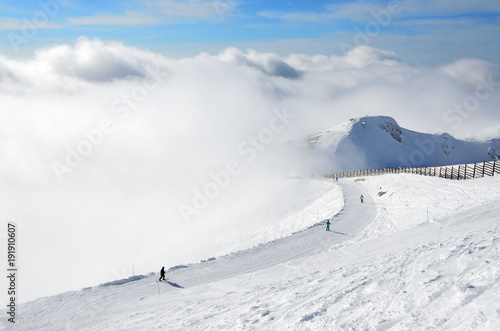 Сочи, горнолыжный курорт Роза Хутор. Лыжники спускаются с горнолыжной трассы "Горицвет" в туман в январе