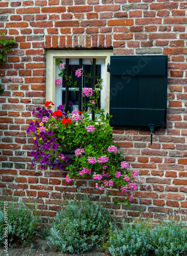 Window with shutters and flowers on brick wall