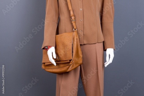 Mannequin with brown clothes and bag. Dummy wearing women brown shirt, trousers and handbag. Female trendy outfit.
