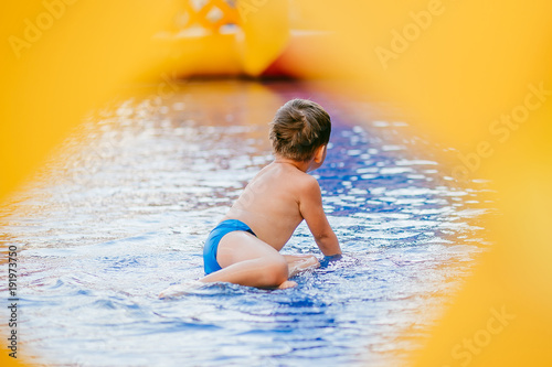 the boy bathes in the children's pool. boy playing in the inflatable pool. through hole, frame.