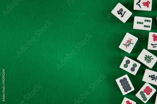 White-green tiles for mahjong on on green cloth background. Emty space on the left