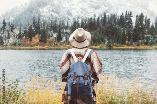 Adventure woman feeling happy among amazing mountains, enjoy the nature landsape. Forest and lake, wearing backpack, hat and poncho, boho and wanderlust style