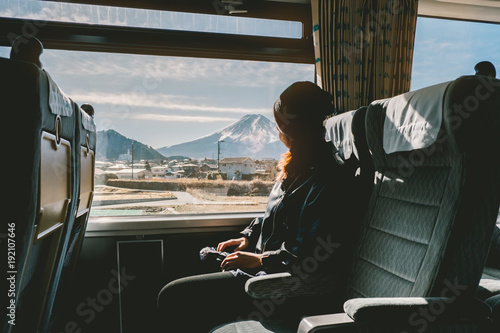 Enjoying travel. Young pretty woman traveling by the train from sitting near the window and looking mountain Fuji. vintage filter. Travel concept