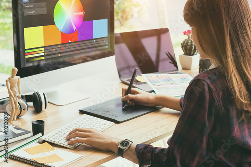 Graphic designer working on creative desk computer while using graphic tablet at desk in the office