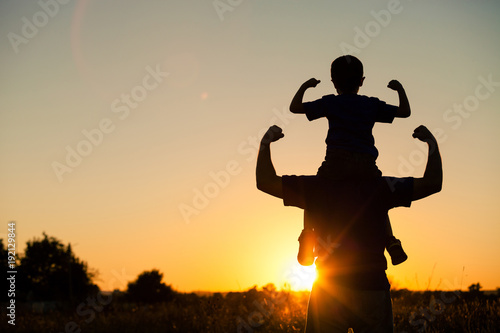 Father and son playing in the park at the sunset time.