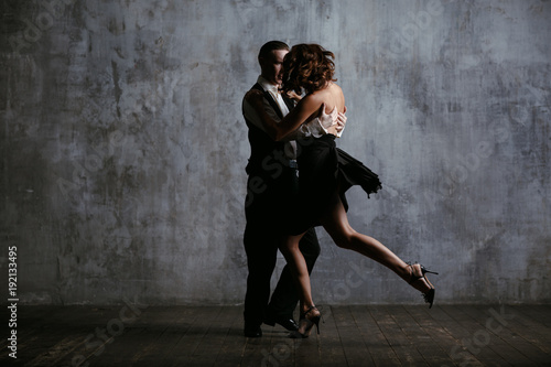 Young pretty woman in black dress and man dance tango