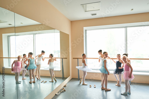 Surprised young ballerinas in studio. Group of cute young ballet girls in dresses looking surprised. Beautiful young ballerinas in different dresses.