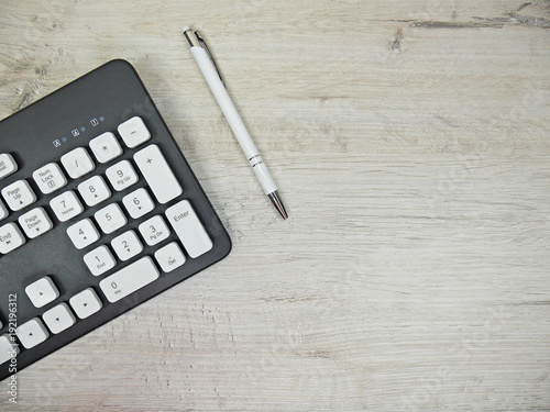 Keyboard and pen on a light wooden background