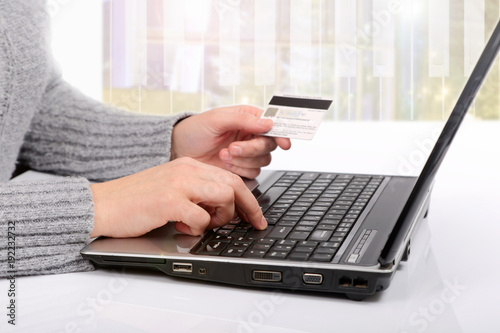 Karta kredytowa w dłoni, zakupy w sklepie internetowym przy pomocy komputera.