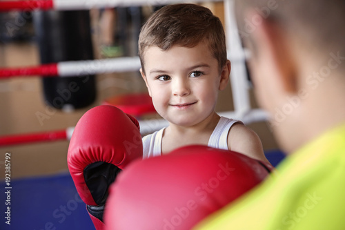Little boy training with coach in boxing ring