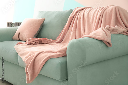 Comfortable mint couch with cushion and blanket in living room