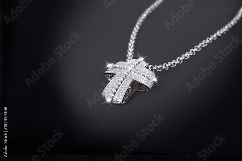 Precious platinum chain with cross diamonds on black background.