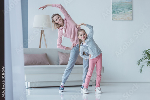 fit mother and daughter doing side bends at home