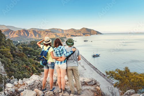 Group of Travelers Man and Woman hugging while standing on the top of the cliff and looking to the sea.
