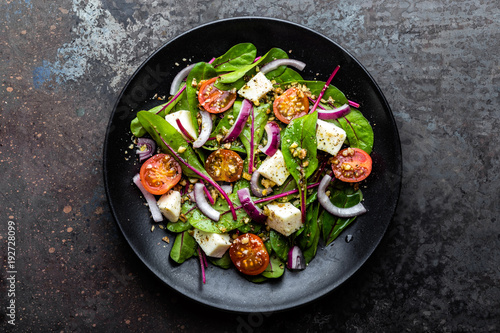 plate of nutritious simple salad with chard, walnuts, soft cheese, onions and oil, top view, space for text