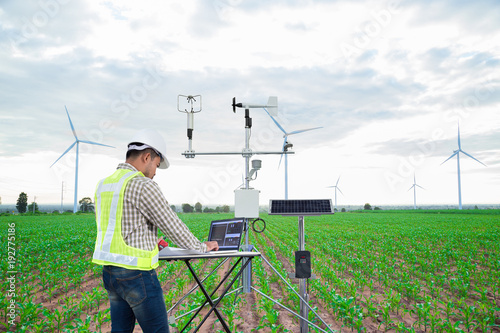 Engineer using tablet computer collect data with meteorological instrument to measure the wind speed, temperature and humidity and solar cell system on corn field background, Smart agriculture concept