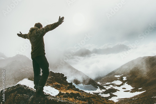 Raised hands Man on foggy mountain summit Travel success lifestyle survival concept adventure outdoor active vacations wild nature
