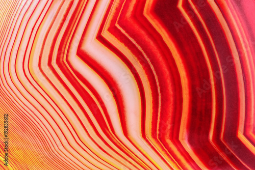 Amazing Banded Red Agate Crystal cross section as a background. Natural light translucent agate crystal surface, Colorful abstract expressive structure slice mineral stone macro closeup