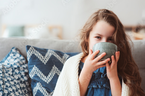 child girl drinking hot tea to recover from flu. Healing kids and protect immunity from seasonal virus, health concept