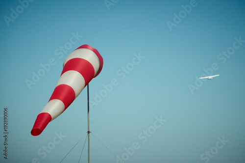 Windsock blown by the wind with airplane on a background