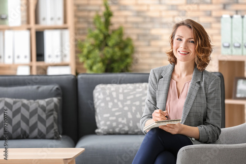 Attractive female psychologist sitting in armchair at office