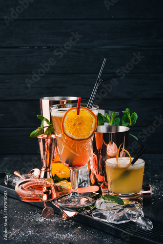 Citrus Alcoholic Cocktails at the Bar. On a black wooden background.