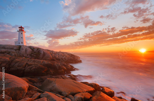 Beautiful Peggy Cove Light House with Sunset, Nova Scotia, Canada. Photo shows tourists watching sunset.