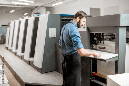 Printing operator working with offset machine at the printing manufacturing