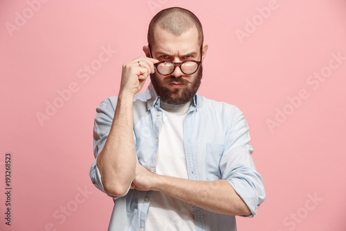 Suspiciont. Doubtful man with thoughtful expression making choice against pink background