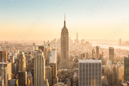New York City. Manhattan downtown skyline with illuminated Empire State Building and skyscrapers at amazing golden sunset. USA.