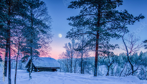 Winter wonderland in Scandinavia with moon at sunset