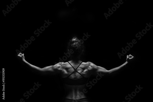Fit woman demonstrate perfect back and shoulders on black background