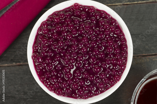 Brazilian dessert called sagu in wine version in a bowl in black wood background seen from above