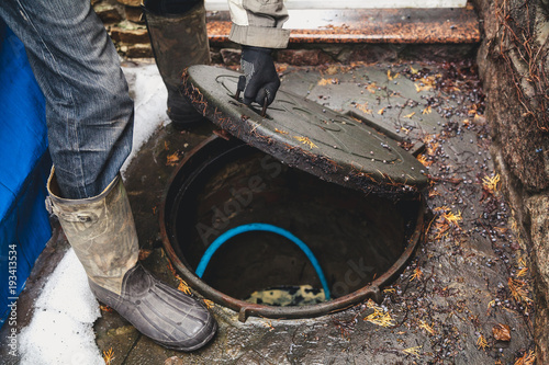 hand opens sewer hatch in yard