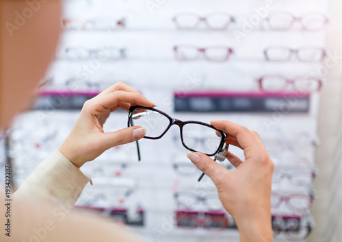 Woman choosing glasses in optician store 