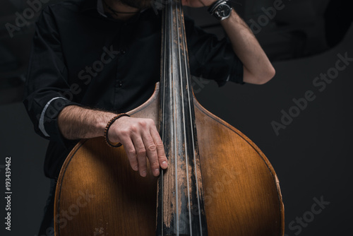 cropped shot of man playing contrabass on black