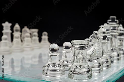 Szachy, szklana szachownica z pionkami na czarnym tle