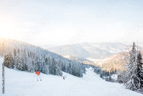 Landscape view on the beautiful Carpathian mountains with ski slope and skiers during the sunny weather