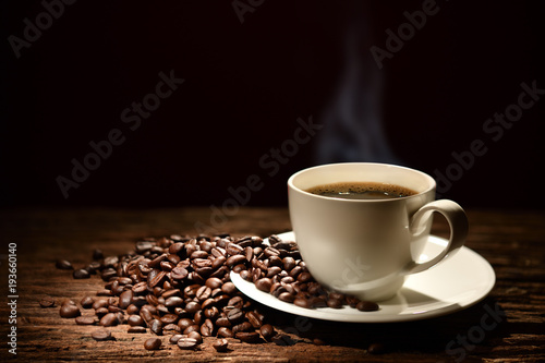 Filiżanka kawy z dymnymi i kawowymi fasolami na czarnym tle
