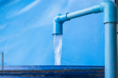 Blue pvc pipe with flowing water in bucket