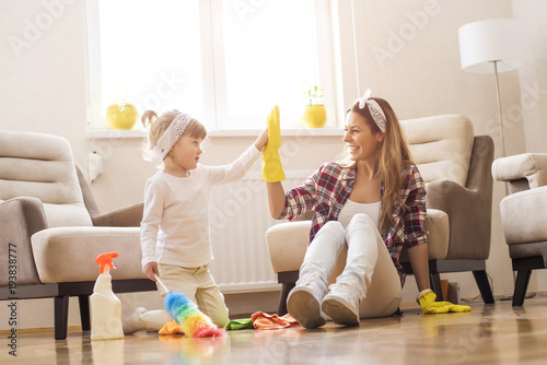 Daughter and mother cleaning home together and having fun.