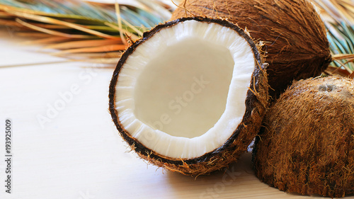 Close up of coconut with palm leaf on wooden background. Copy space.