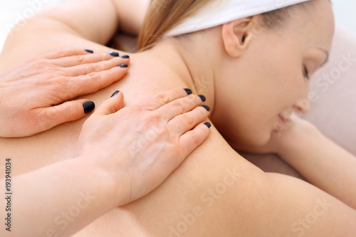 Masaż relaksacyjny pleców. Masażystka masuje plecy kobiety w salonie masażu.