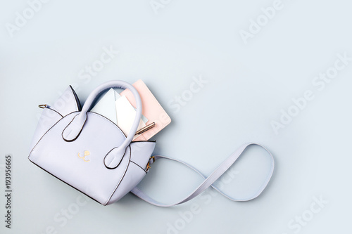 Cute blue handbag with , notebook and feminine accessories . Flat lay, top view. Spring fashion concept in pastel colored