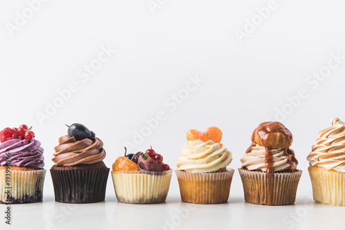 close up view of various sweet cupcakes isolated on white